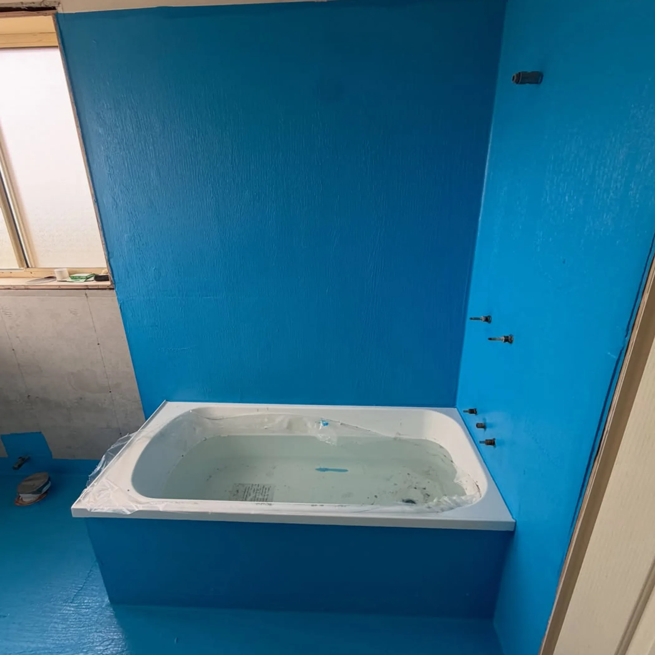 wet-area bathroom with bathtub and blue waterproofing